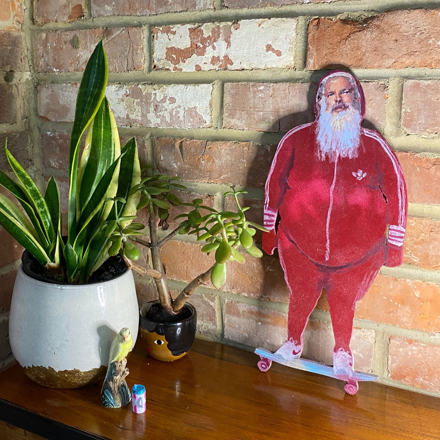 Rick Ruben a red tracksuit on a skateboard, an oil painted panel with plants and a brick wall in the background.